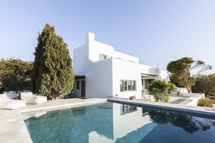 white villa with pool and large tree