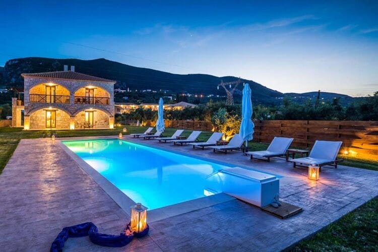rustic villa with lit up pool at dusk