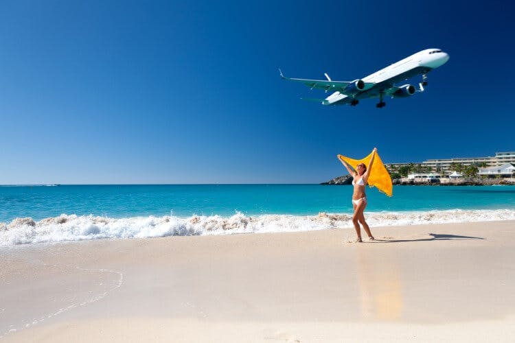 woman on beach with low flying plane