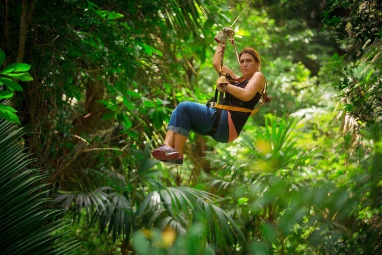A woman ziplines through the rainforest canopy