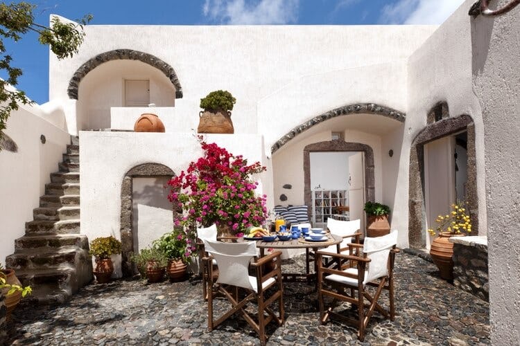 white villa with courtyard with dining set and pink flowers