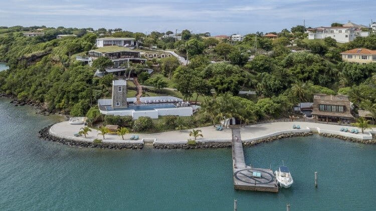 Mount Hartman Bay Estate exterior shot of large home, jetty with boat docked, and the sea