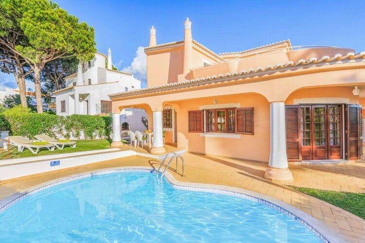 orange villa with white pillars and pool