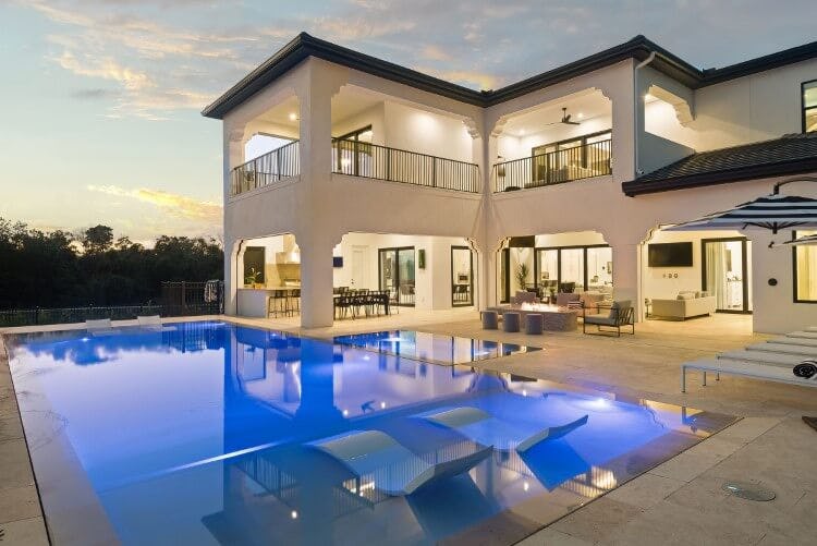 white lit up villa at dusk with pool and pool loungers