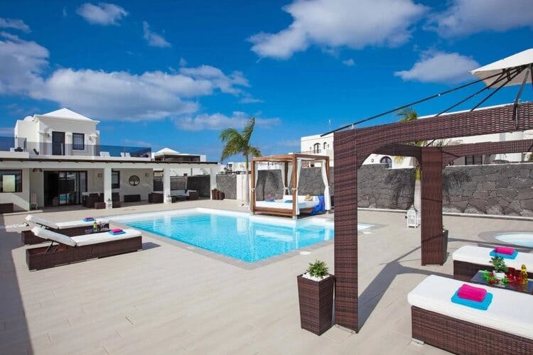 large patio with sun beds, white villa and pool