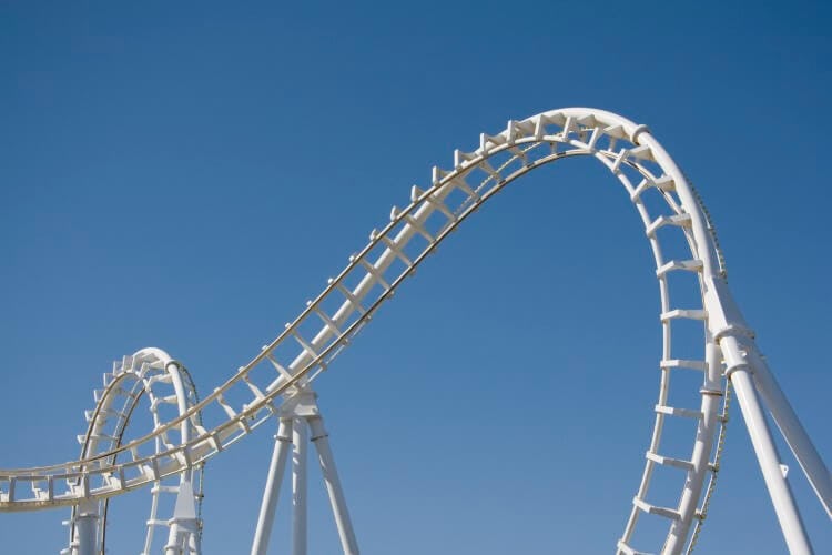 A white roller coaster track against a cloudless blue sky
