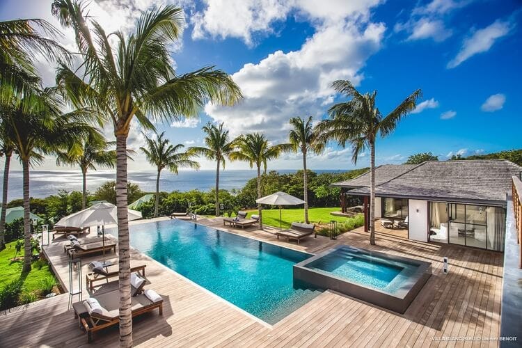 deck of villa with pool, hot tub, palm trees and ocean in distance