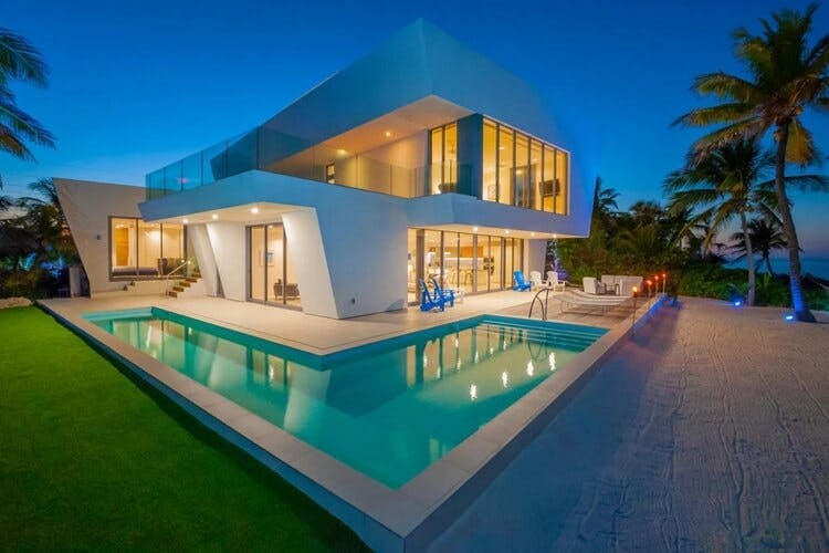 modern villa at dusk with wrap around pool