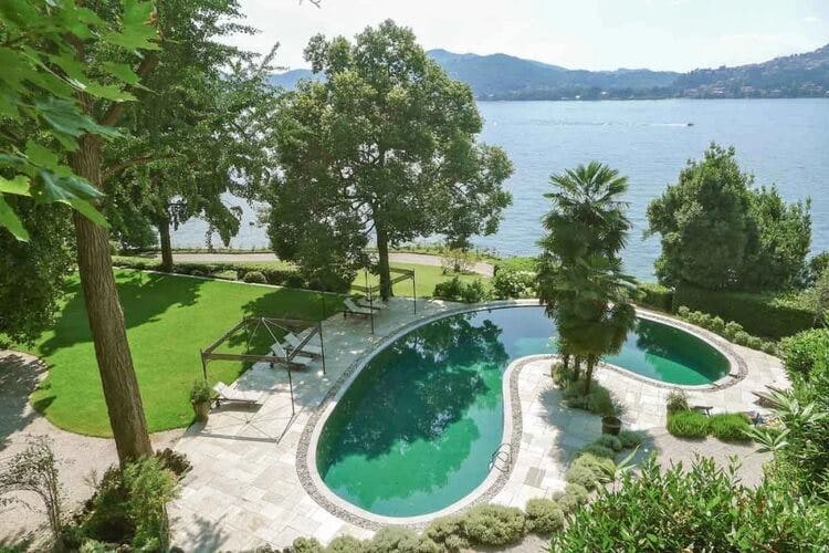 pool surrounded by trees with lake and mountains in background