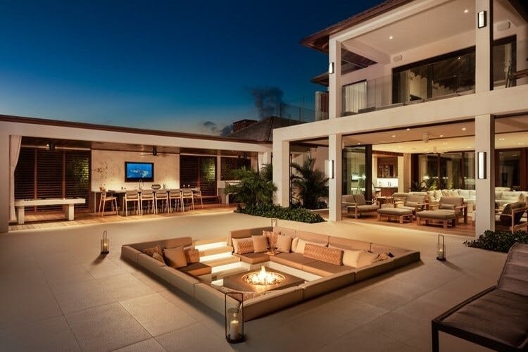 a white villa at dusk with a modern fire pit