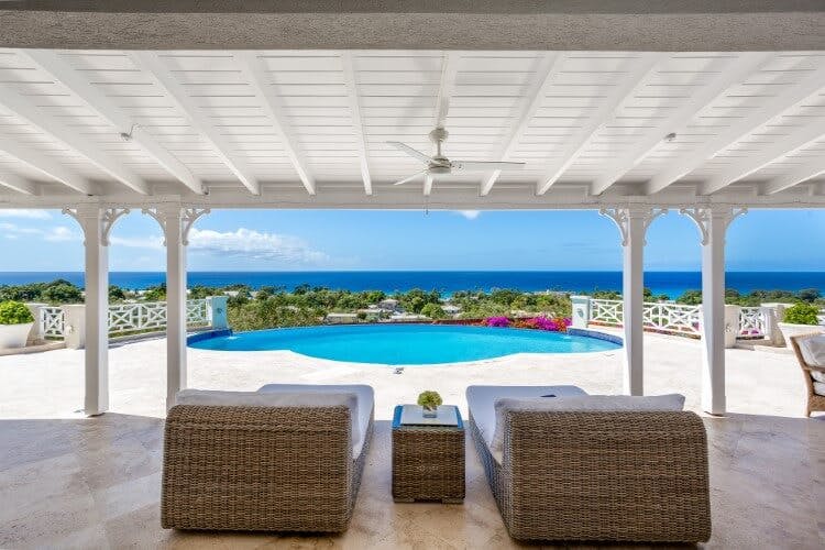 Aquilae vacation rental view of the pool, outside seating area, and the Caribbean Sea beyond