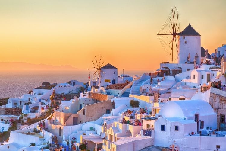 The hilltop town of Oia in Santorini with white cube houses and windmills at sunset