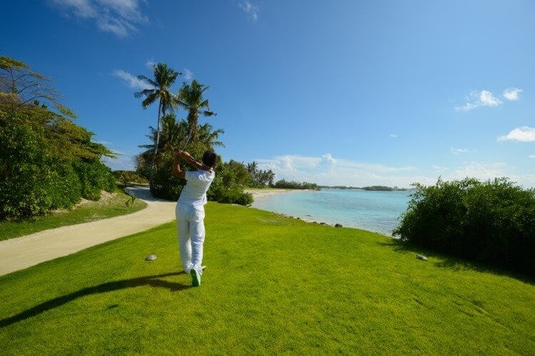 person playing golf with sea in background
