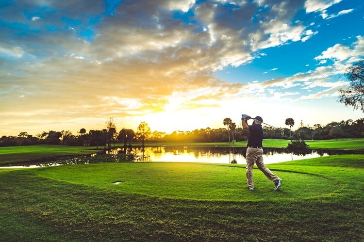 someone playing golf at sunset