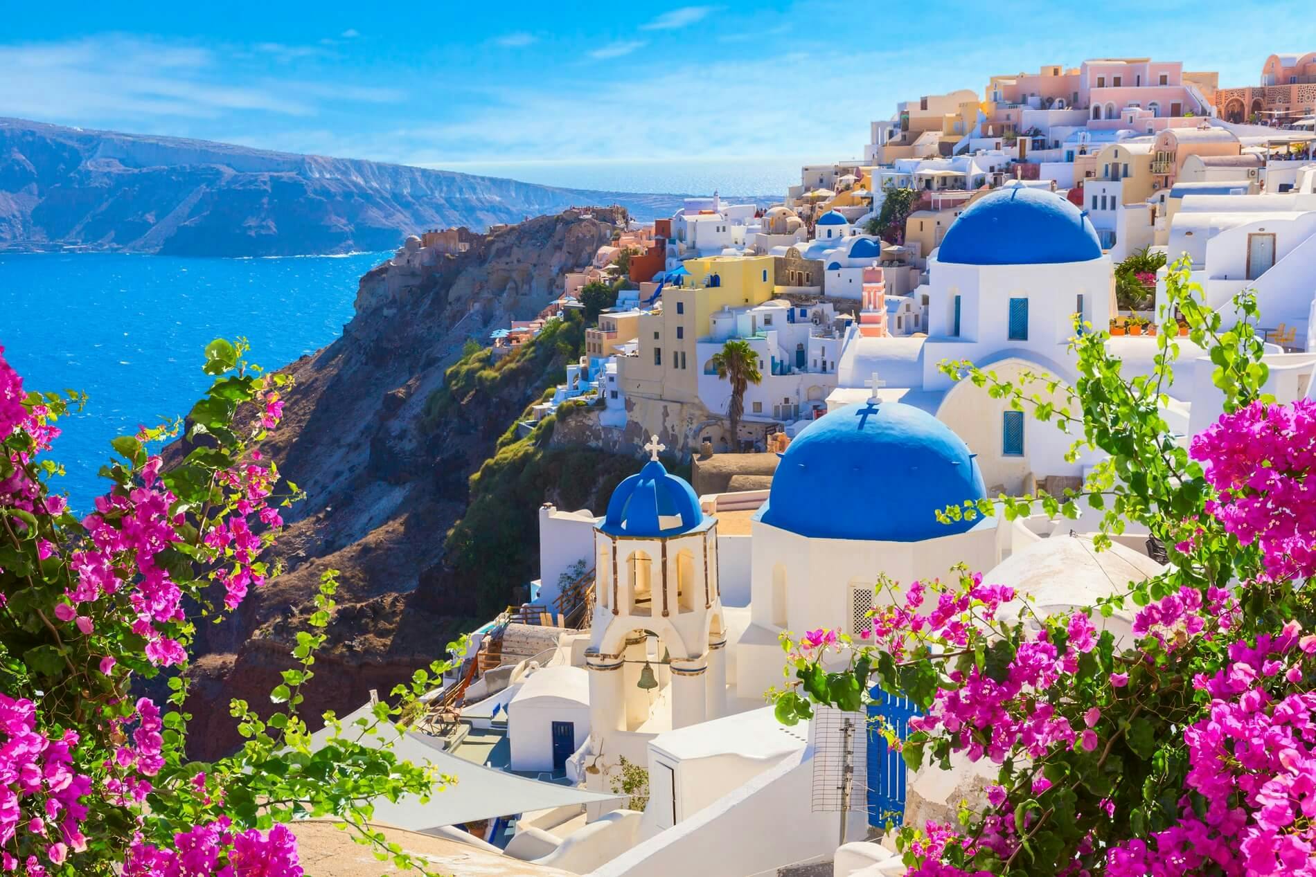santorini with white walls, blue roofs and pink flowers