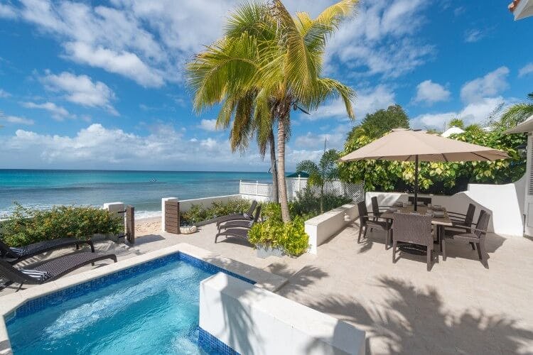 pool and dining set on patio next to beach