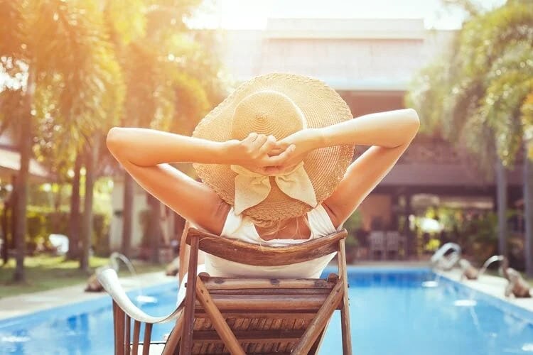 Woman in hat relaxing next to pool