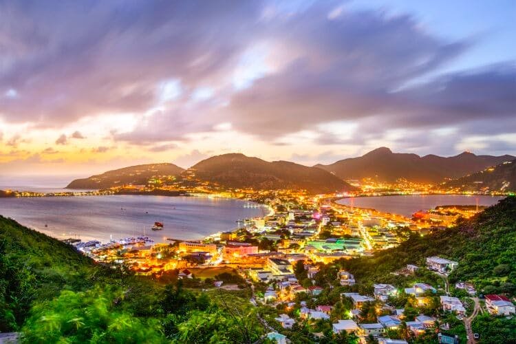 Philipsburg in Sint Maarten at dusk - the city lights are on, bathing the sky and landscape in a warm golden glow, as soft purple clouds streak across the twilight sky