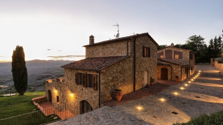 rustic tuscany vacation rental lit up at dusk