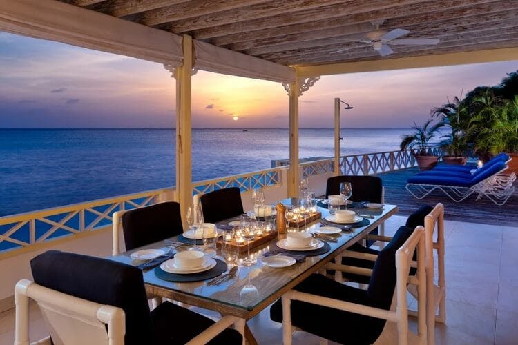 dining set on covered terrace overlooking ocean at sunset