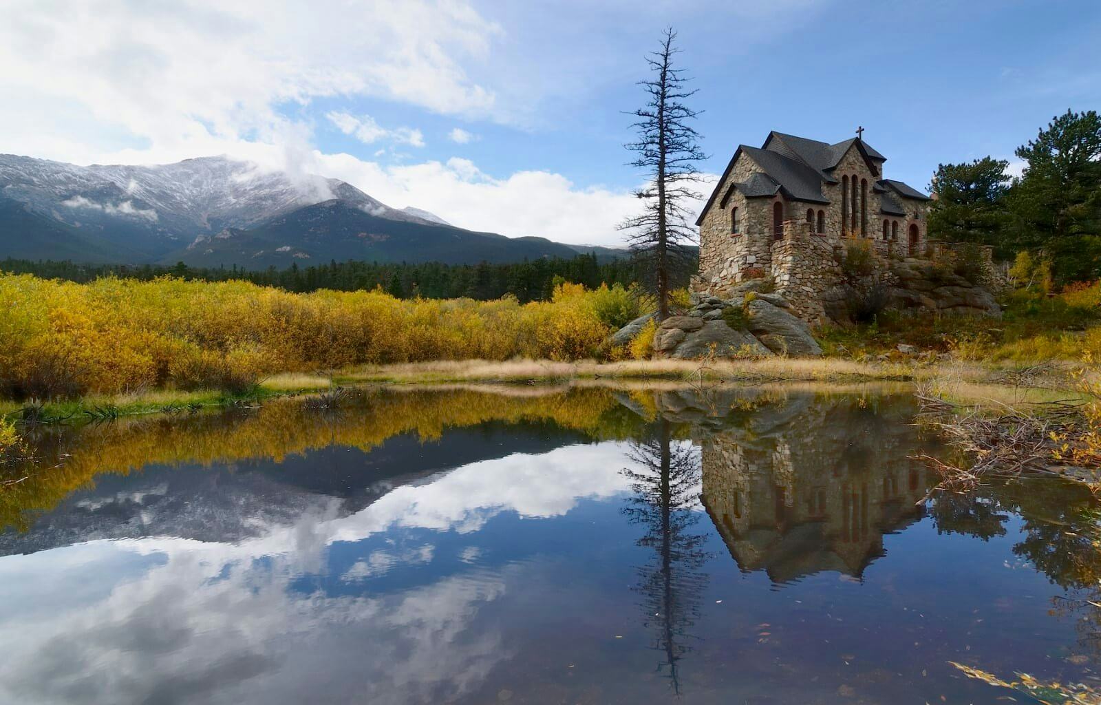 Rocky Mountains church by a still lake with mountains in the background in Estes Park