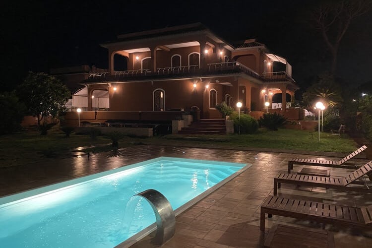 lit up villa at dusk with pool in foreground
