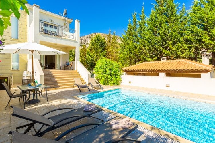 white villa with steps down to pool and loungers