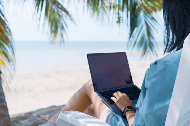 woman on laptop on beach