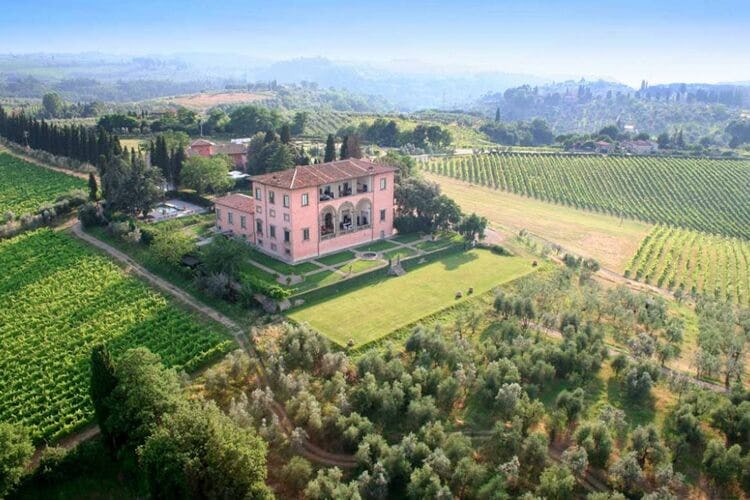 aerial view of a large pink mansion in tuscan countryside