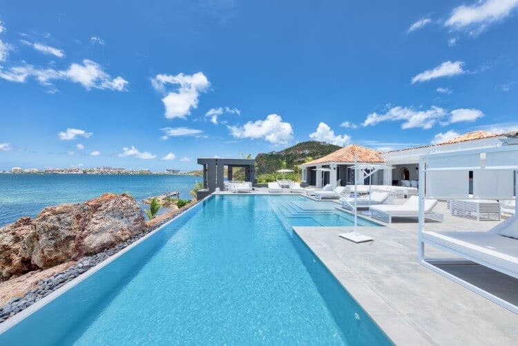 Mirabelle villa - image of the home's private pool, with an infinity edge overlooking a rocky outcrop and the Caribbean Sea. There are sun loungers on the very edge of the pool