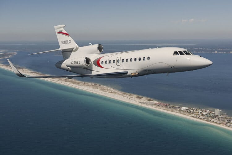 Falcon 900LX/EX private jet flying over a beach
