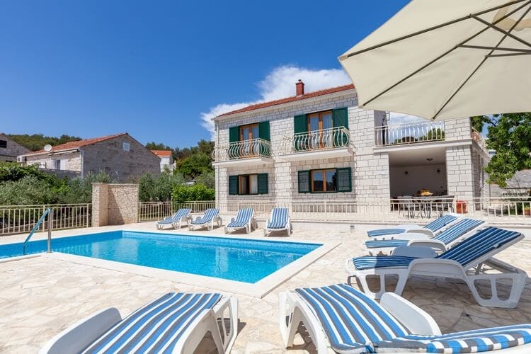 stone villa with green shutters, pation with pool and loungers