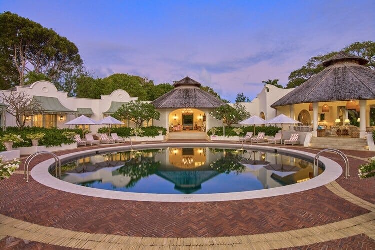 grand white villa with round pool at sunset