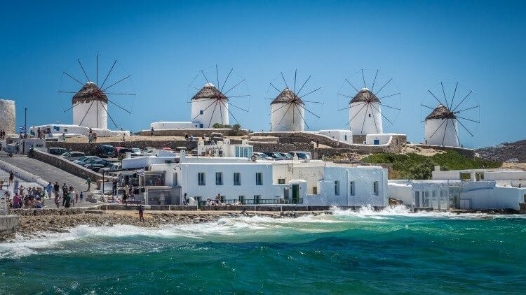 Five Mykonos windmills in a row above the old town and sea