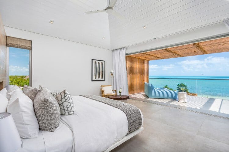 bedroom with open door leading to balcony overlooking ocean
