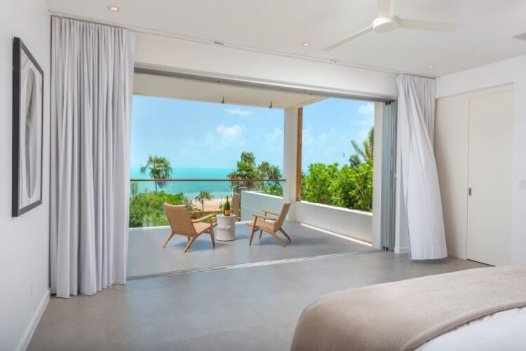 bedroom with open doors leading to balcony overlooking ocean