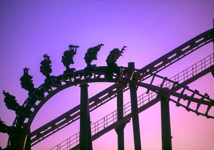 People riding a roller coaster at dusk