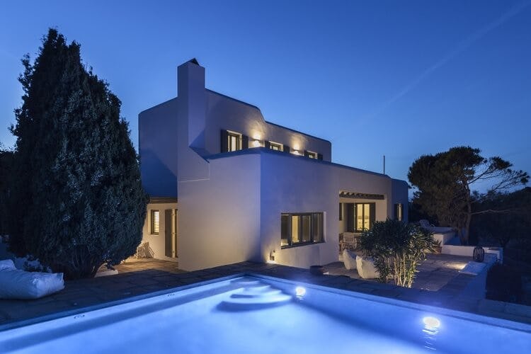 white villa at dusk with lit up pool