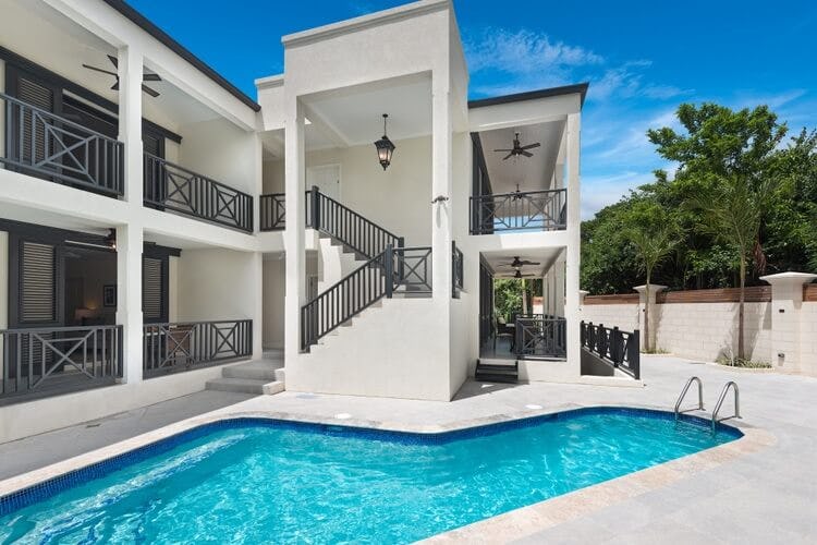 white villa with black railings and pool in patio