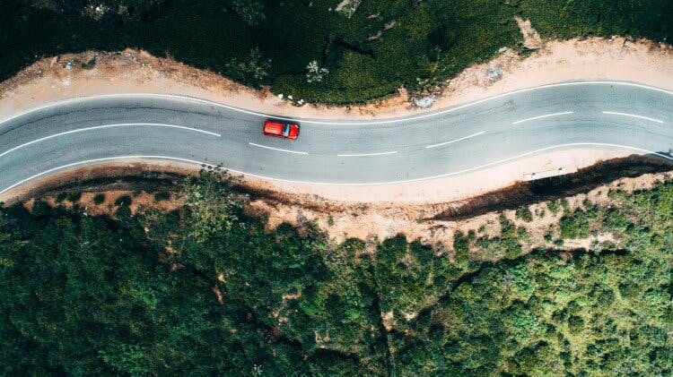red car on tropical road aerial view