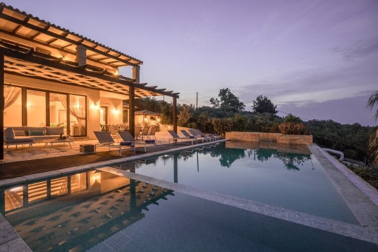 lit up villa at dusk with pool