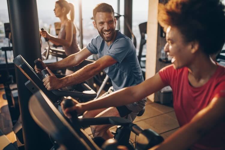 Stock image of a man and a woman working out on static bikes