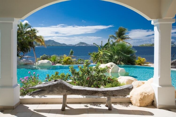 La Salamandre vacation rental - image of columed archway looking out over the home's private pool and beyond to a view of the Caribbean Sea and mountains in the background
