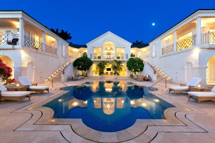 grand white mansion with two staircases and pool in middle