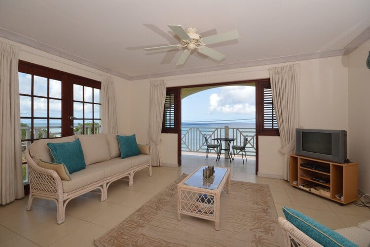 living room with open doors leading to balcony with bistro set and ocean view