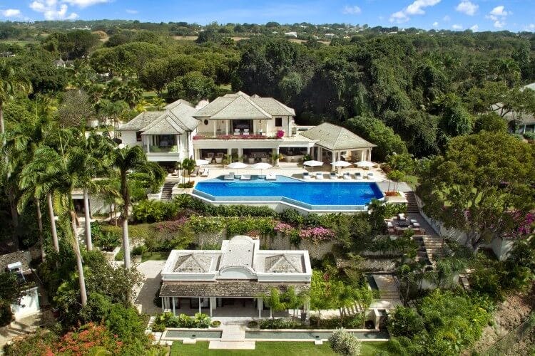 Exterior shot of Sandy lane Sanzaru villa, a large home with a big private infinity pool surrounded by forest