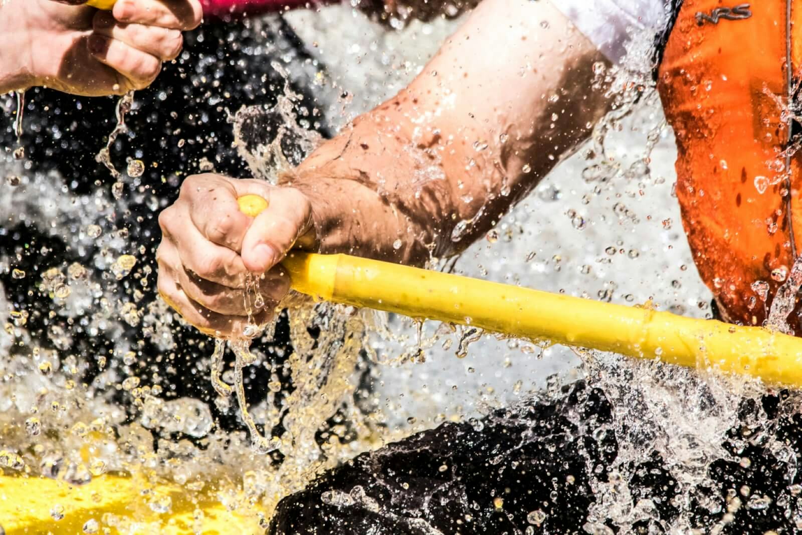 A close-up of a man's hand holding a rafting paddle