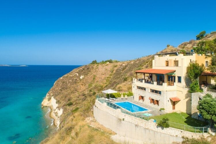 pale yellow villa on cliff overlooking ocean