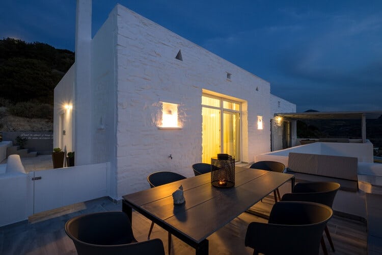 white villa with lit up doorway at dusk and seating area