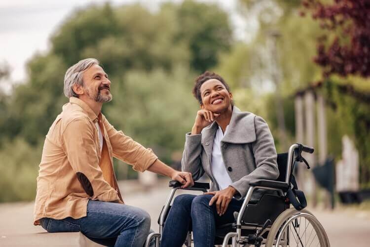 man sitting and woman in wheelchair smiling
